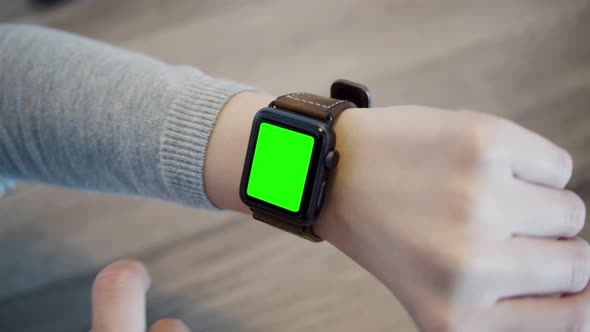 Arm of a woman with smartwatch - close up - slow motion - green screen - wooden table background