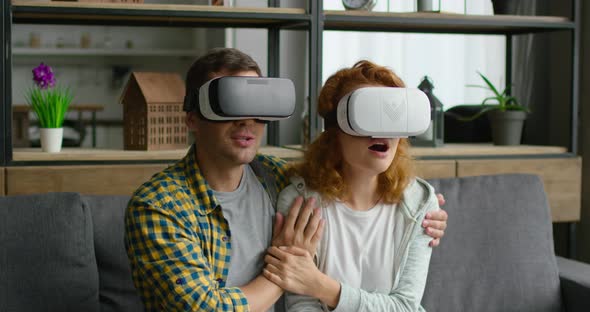 Young Couple Is Watching Breathtaking Video in Virtual Reality Headset at Home