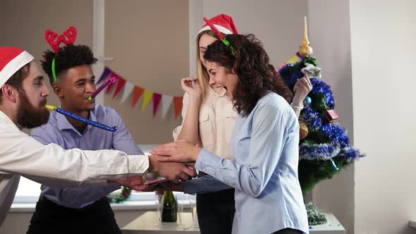 Young Attractive Woman Standing with Her Eyes Closed By Her Female Colleague While Male Workers