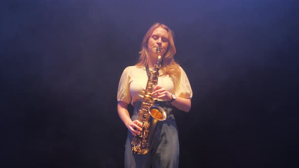 Young Caucasian Woman Playing Solo on Saxophone Under Stage Lights in Haze