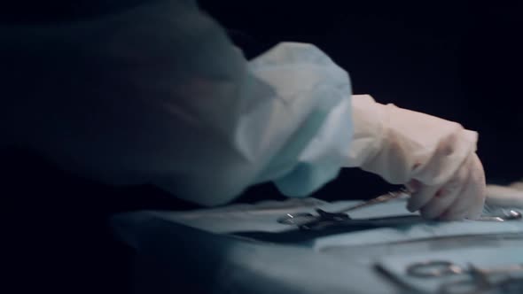 Assistant Handing Surgery Tools to Practitioner Dark Operating Theater Closeup