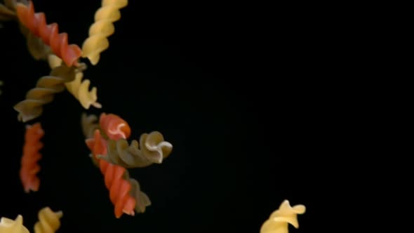 Dry Colored Pasta Fusili Falling Diagonally on a Black Background