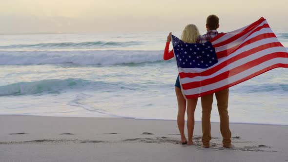 Couple standing with American flag at beach 4k