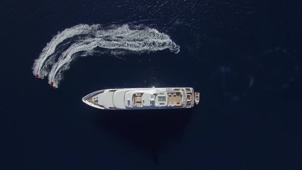 Aerial view of two Jet Ski ride around Super Yacht at Sunset.