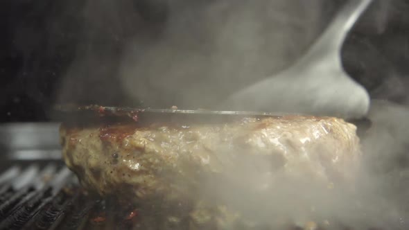 Cook Hand Turns Over And Presses A Fried Beefsteak On A Grill