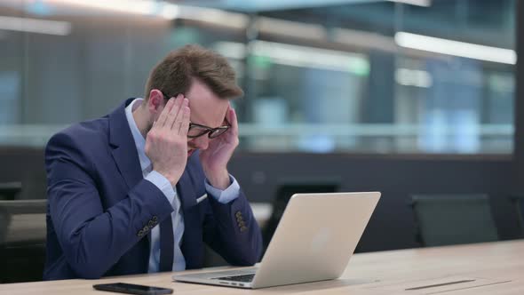 Middle Aged Businessman with Laptop Having Headache