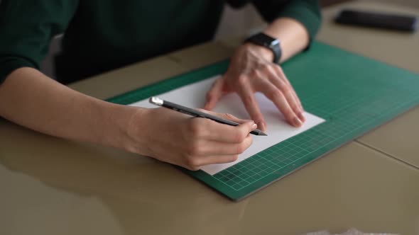 Closeup Highangle View of Hands of Unrecognizable Female Making Mark on White Paper on Green Rubber