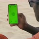 African Maasai Male Hand Holding a Smartphone with Green Screen and Swiping in the Front of Desert - VideoHive Item for Sale