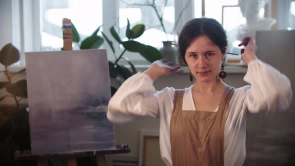 Young Woman Artist Lets Her Hair Out of Her Hairstyle and Looks in the Camera