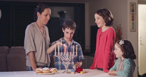 Kids and their mother lighting Hanukka candles