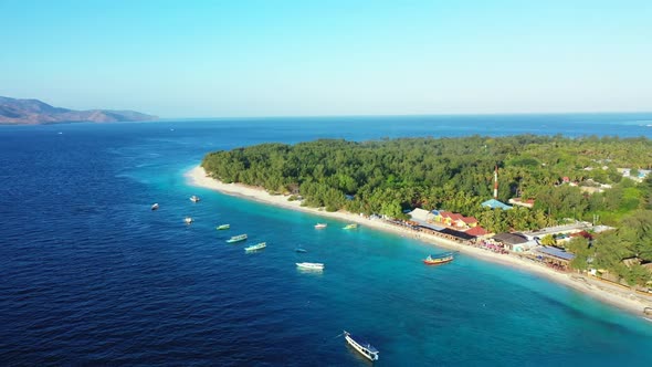 Aerial drone shot tourism of idyllic tourist beach break by blue ocean and white sandy background of