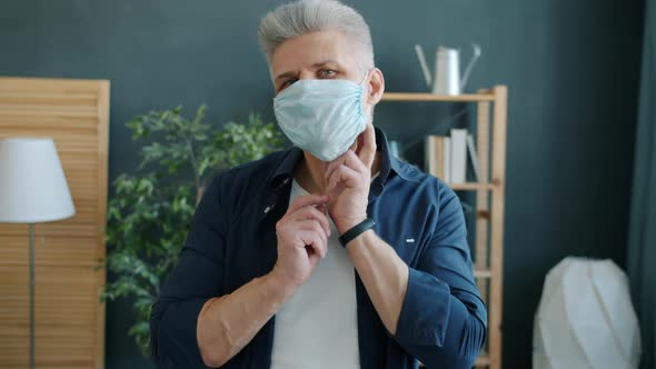 Portrait of Miserable Man Scratching Face Under Medical Protective Mask Then Taking It Off at Home