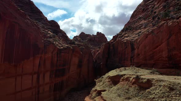 Drone flying low inside a red rock slot canyon. Drone slowly going up to capture the red isolated la