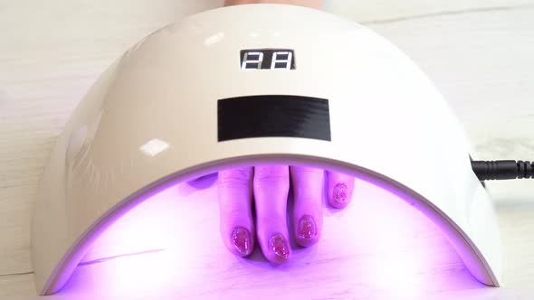 Girl Placed Hand Under an Nail Polish Curing Lamp and Waits for the Nail Polish to Harden