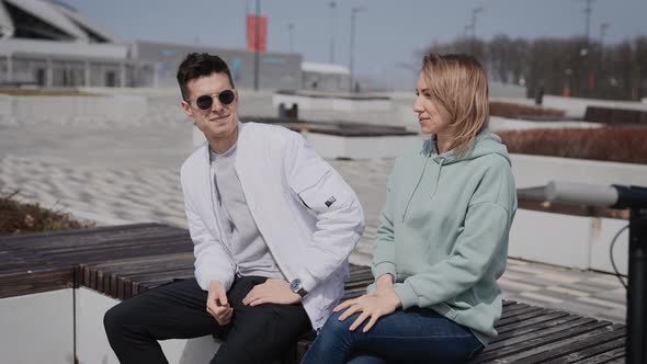 A Man and a Woman are Sitting on a Bench and Have a Conversation