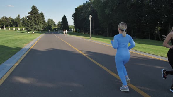 Fit Female Running Along Park Alley in Sunlight