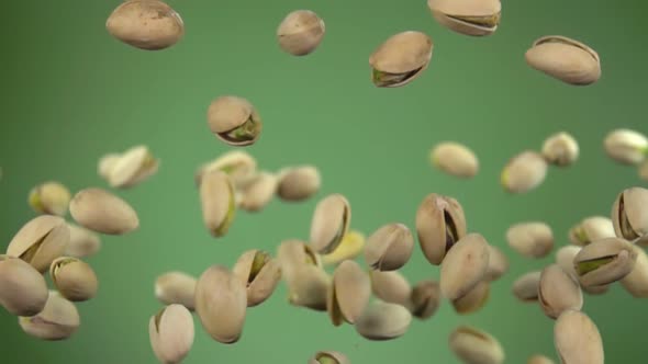 Close-up of Salted Pistachios Flying Up on a Green Background