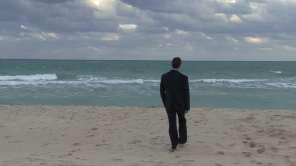 Male walking into ocean in suit