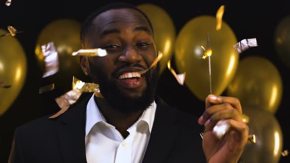 Smiling Black Man With Bengal Light Standing Under Falling Confetti