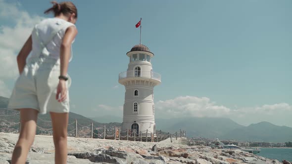A Teenage Girl in Turkey in the City of Alanya Walks Over the Stones to the Lighthouse