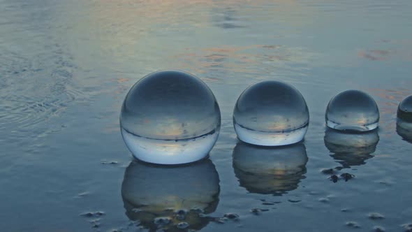 Four Glass Balls Are Placed In The Middle Of A Shallow River.