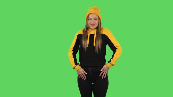 Modern Girl in Yellow Hat Is Smiling and Showing Heart with Fingers Then Blowing Kiss. Green Screen