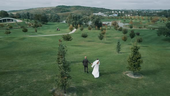 Newlyweds stroll through the expanse of a beautiful golf course in Europe.