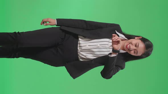 A Smiling Asian Business Woman Looking At A Watch While Walking Through Green Screen In The Studio