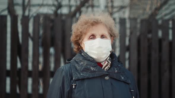 Elderly Woman in a Respirator Protection Mask is Walking the Street