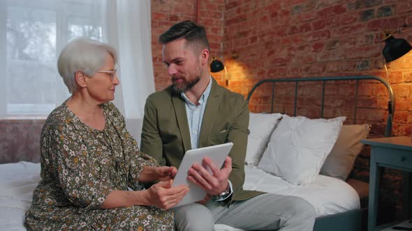 Relatives with Generational Gap Sitting Bonding and Watching Old Photos on Silver Tablet