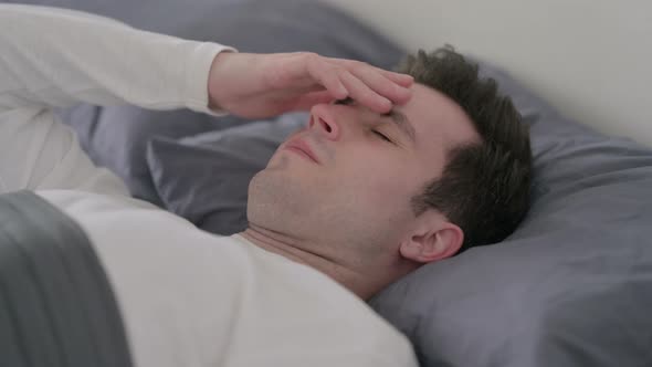 Man Having Headache While Sleeping in Bed Close Up