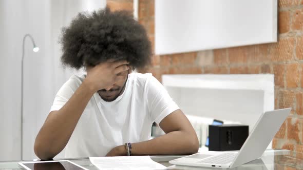 Stressed African Man Sitting in Loft Office