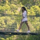 Brunette with Long Curly Hair Walks Along Suspension Bridge - VideoHive Item for Sale