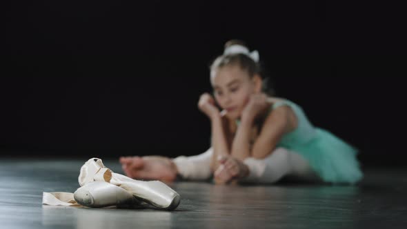 Unfocused Blurry View Tired Barefoot Girl Child Ballerina Sitting on Floor in Dance Class Feels