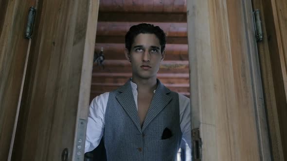 Attractive young fashion man in a suit slowly opens the wooden door. Slow motion