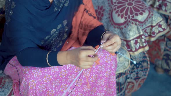 Traditional Indian woman watching her knitting and start to knit new row with black wool