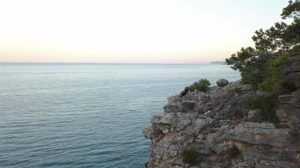 Aerial View of Young Woman on Rock Cliff Against Sea