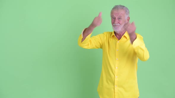 Happy Senior Bearded Businessman Presenting Something and Giving Thumbs Up