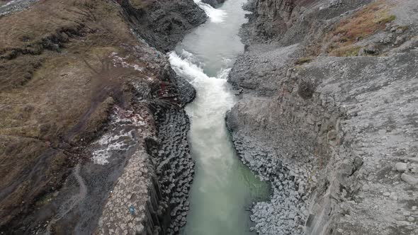 Slow aerial pan up revealing Studlagil Canyon, Iceland carved by glacial river.