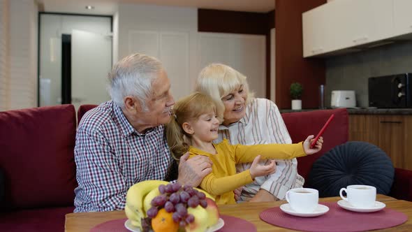 Senior Couple Grandparents with Child Granddaughter Making Selfie Photos Together on Mobile Phone