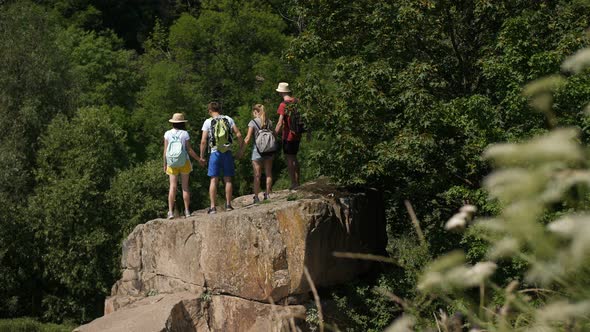 Hikers Cheering with Arms Raised on Top of Mountain