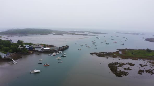 drone aerial of lobster fishing boats in marina ocean bay with pier and islands foggy weather 4k 30p