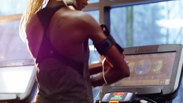 Fit Woman with Smartphone Exercising on Treadmill