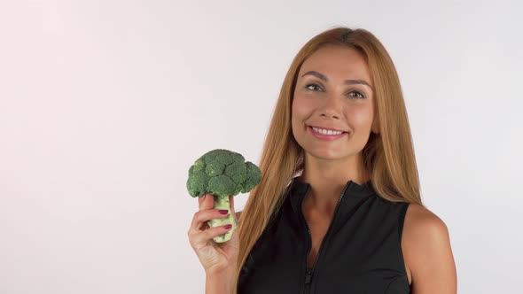 Cheerful Healthy Beautiful Woman Holding Broccoli, Showing Thumbs Up