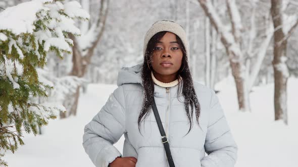 Young Black Woman in White Jacket Walks in Winter Forest