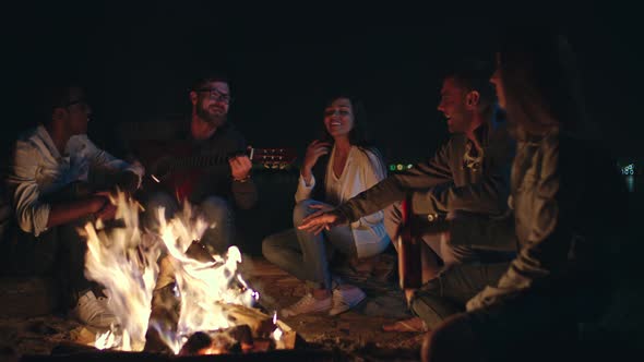 Friends Singing Song by Campfire while Camping at Night