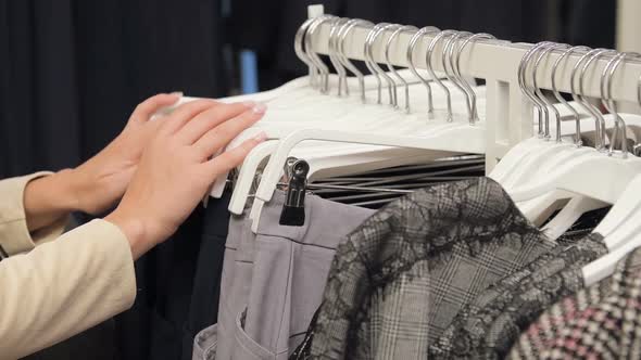 Closeup of Female Hands Plucked a Hanger with Clothes