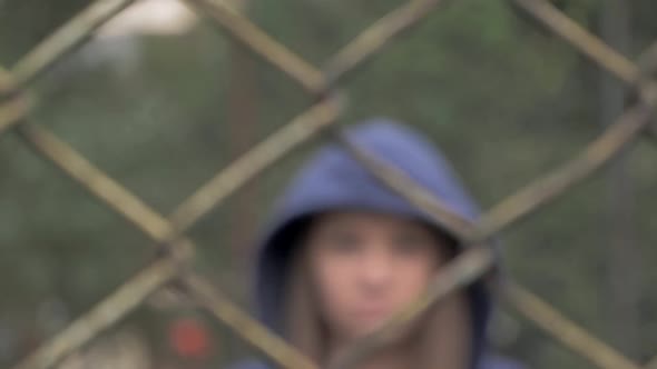 Portrait of Moody and Sad Blonde Caucasian Girl Behind the Iron Fence