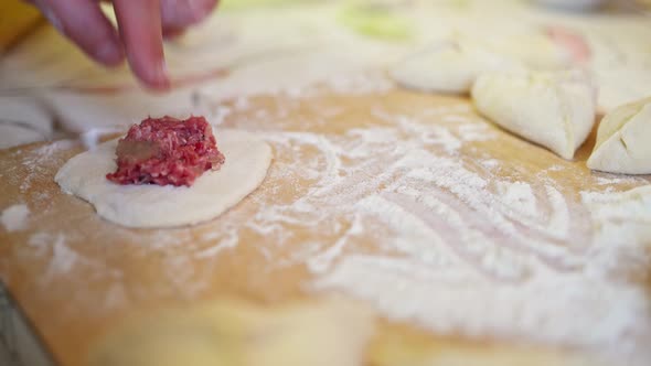 Female Hands Add Meat Filling to a Piece of Dough