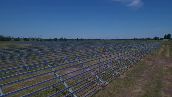 Drone is Flying Over a Field with Many Rows of Solar Panel Mounting Racks